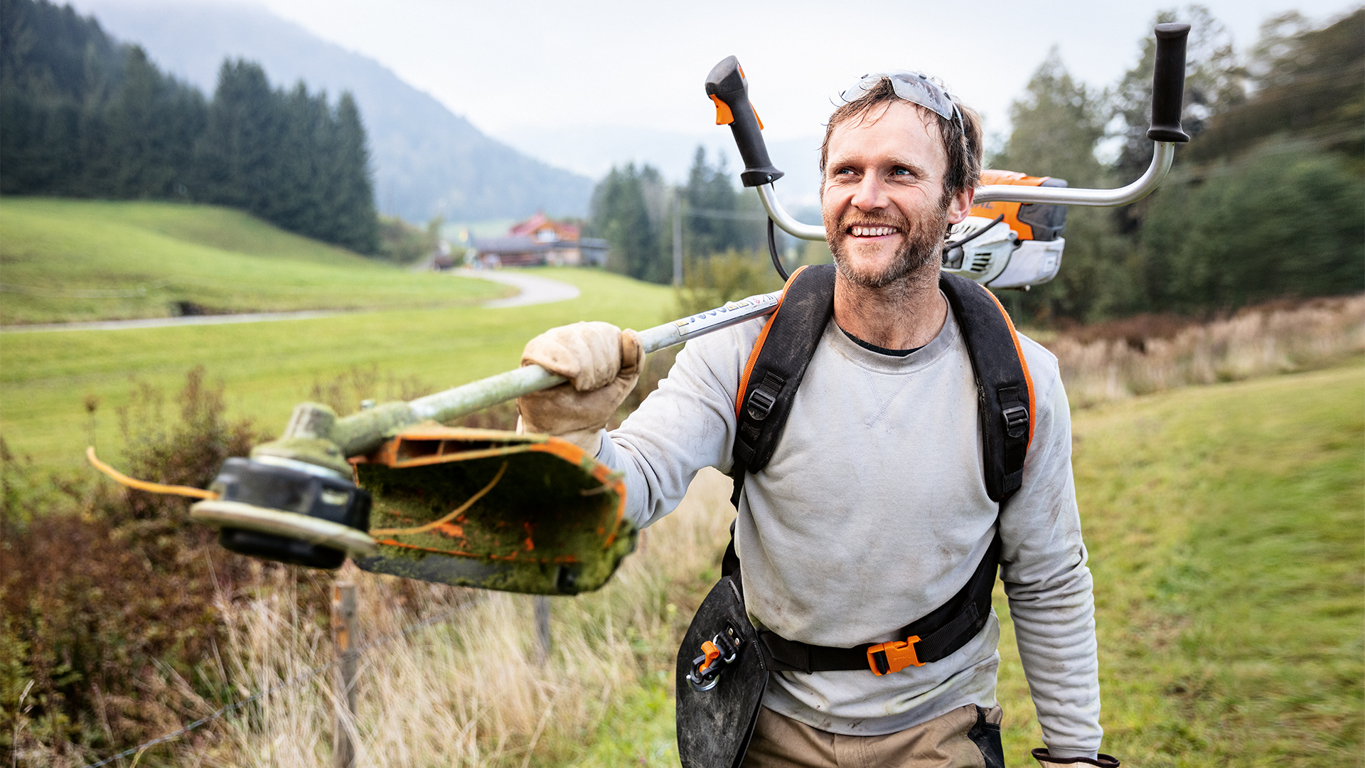 Mann mit STIHL Motorsense und Universalgurt Advance PLUS auf Wiese