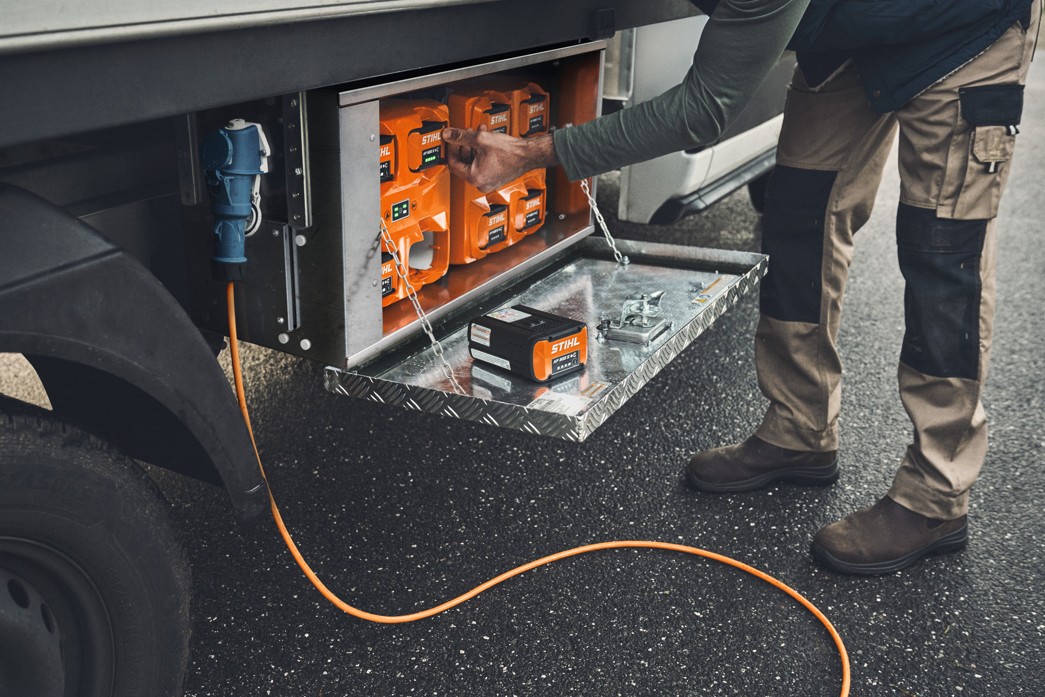 Un homme sort une batterie STIHL AP 500 chargée de la boîte de chargement