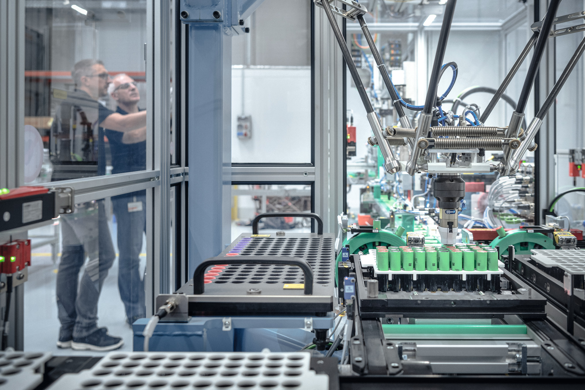 Deux hommes dans l'atelier de fabrication de batteries STIHL entourés de machines et de robots