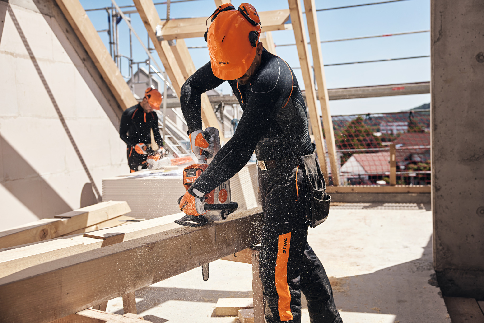 A person in personal protective equipment sawing a wooden plank.