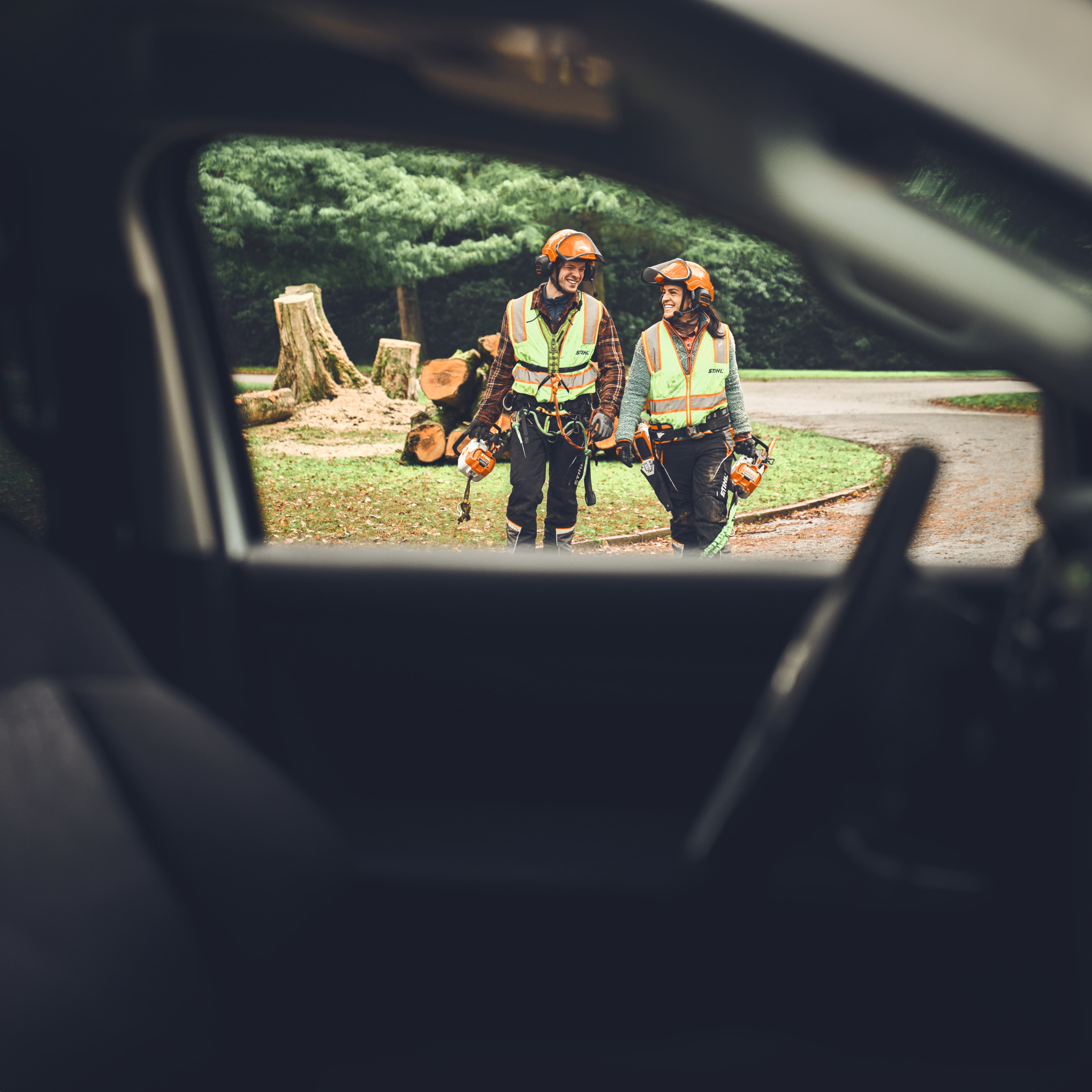Man and woman on the way to the car with STIHL MSA 190 T and MSA 220 T cordless chainsaws and GTA 40 cordless jigsaw