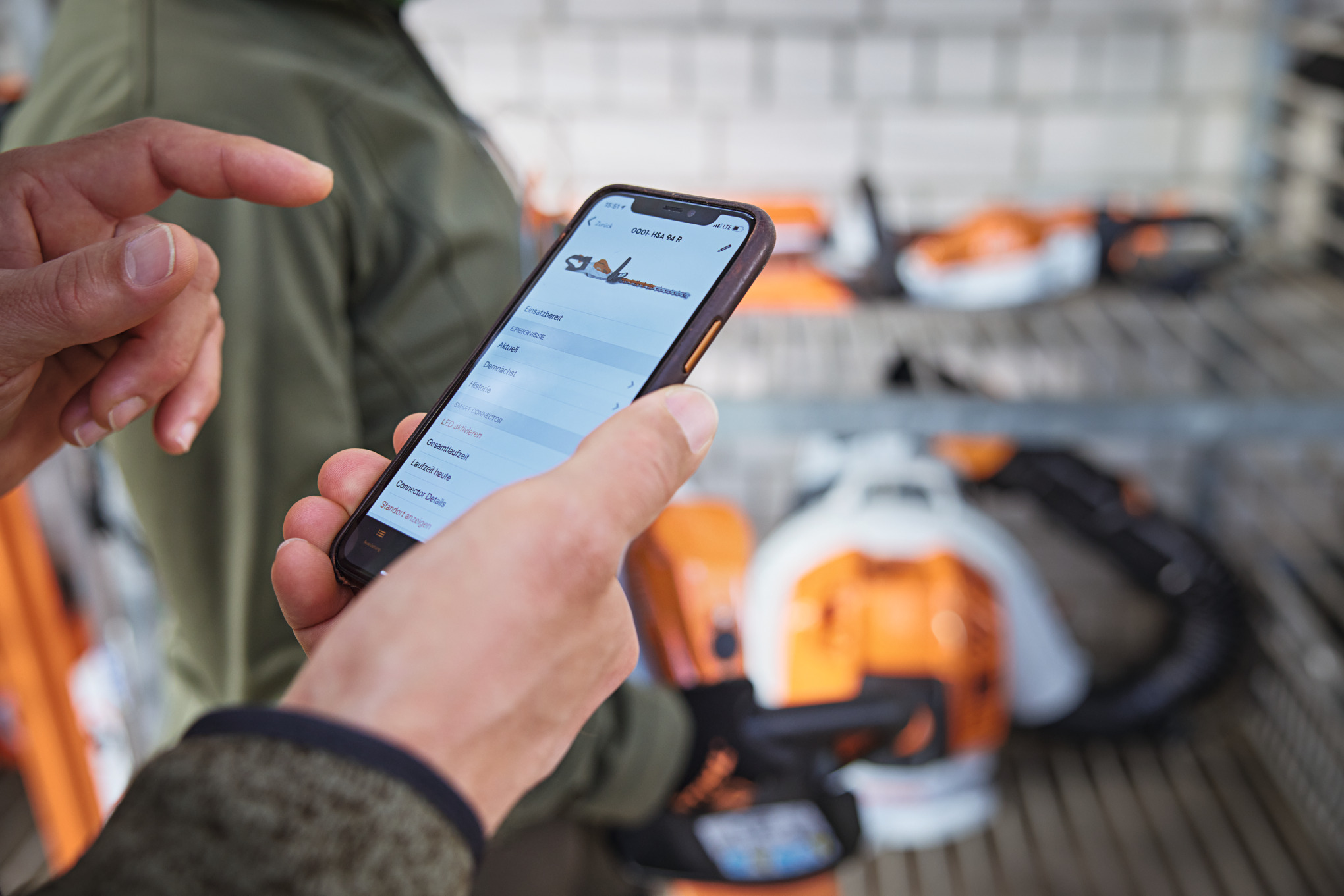 Personne avec un smartphone regardant une tronçonneuse dans l’application STIHL connected