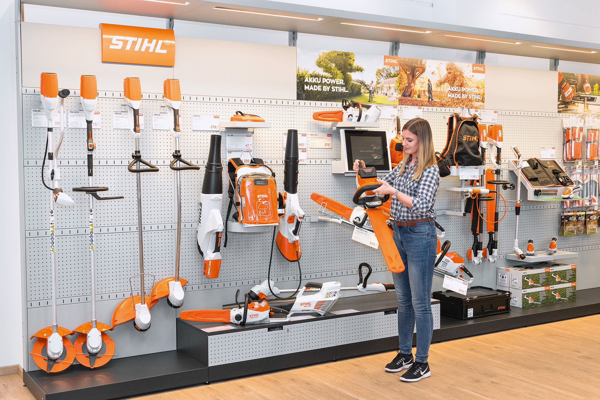 A young woman in front of product shelves at a STIHL dealer requesting a free trial with a STIHL chainsaw