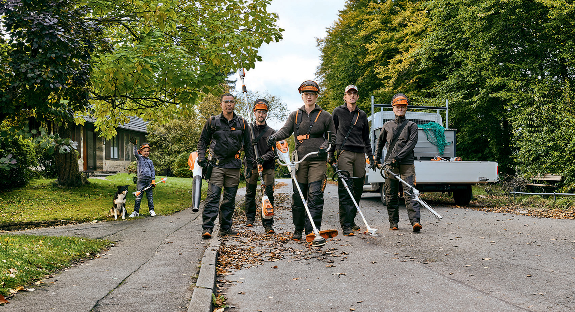 A gardening and landscaping team with STIHL professional cordless power tools walking along a street.