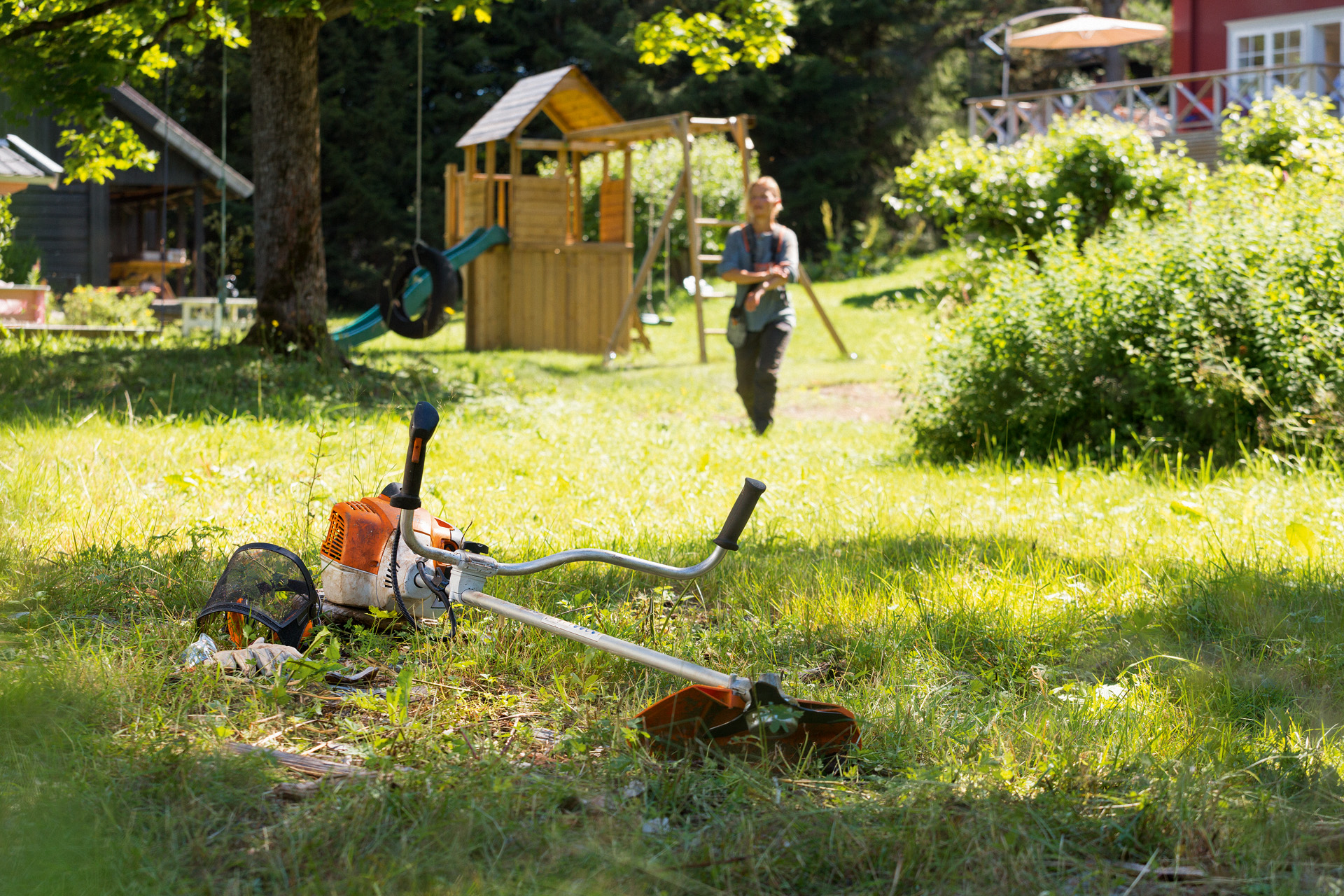 La débroussailleuse STIHL&nbsp;FS&nbsp;240 est posée dans l’herbe, un homme se prépare à l’entretien en arrière-plan