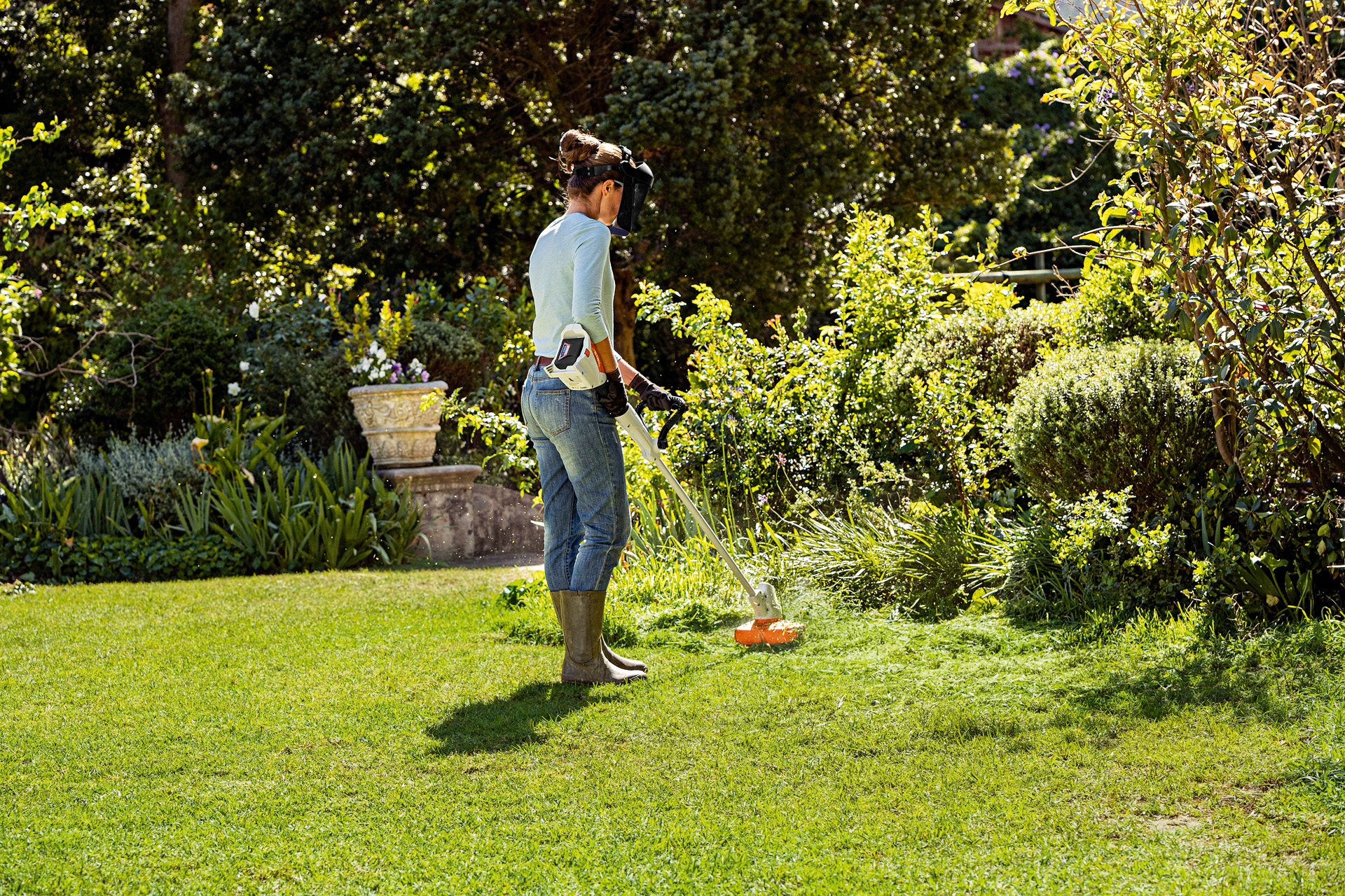 Femme coupant la bordure d’une pelouse avec le coupe-herbes STIHL FSA 57