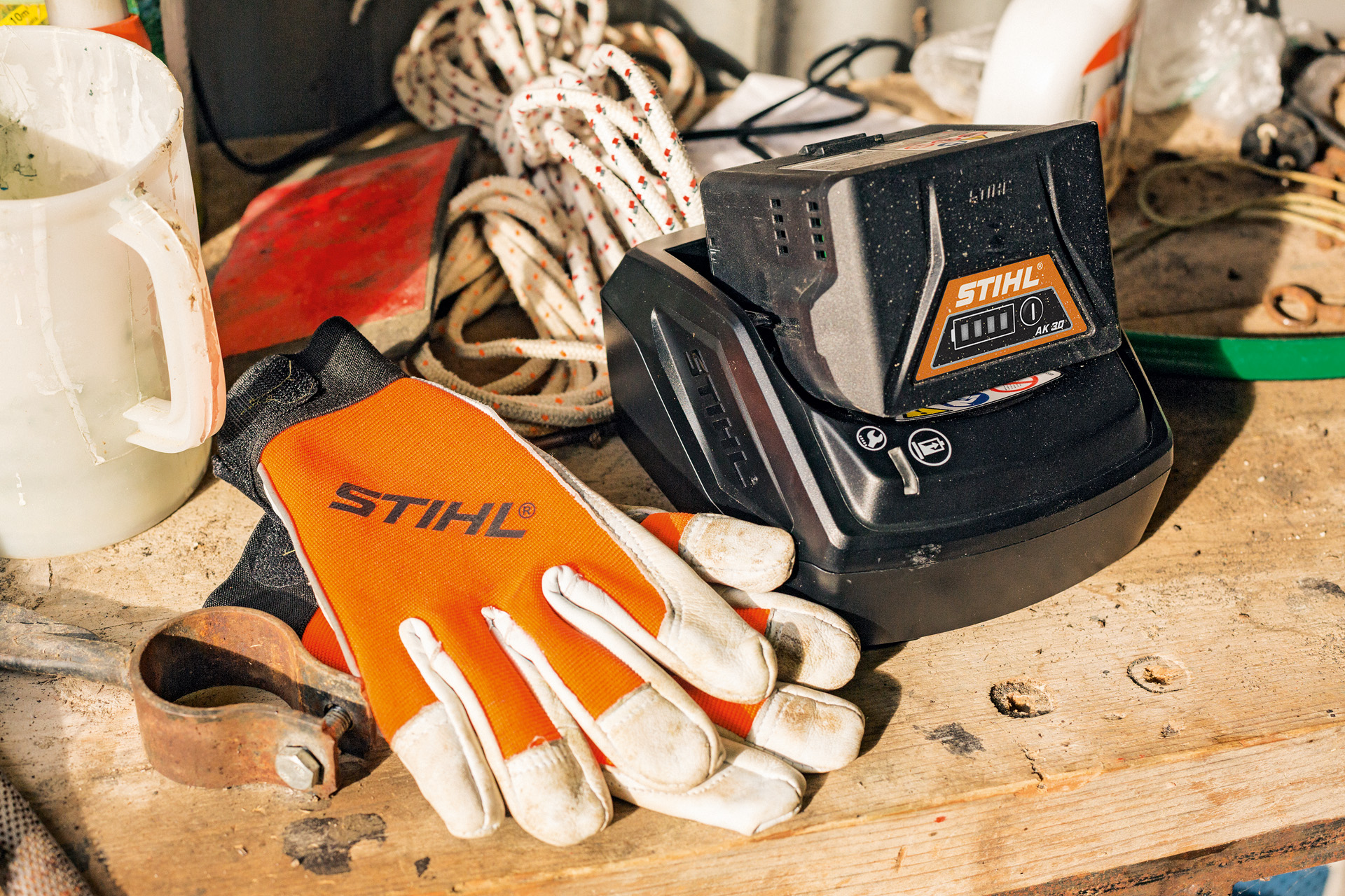 Chargement de batteries lithium-ion de la série AK à côté de gants et d’outils de travail STIHL