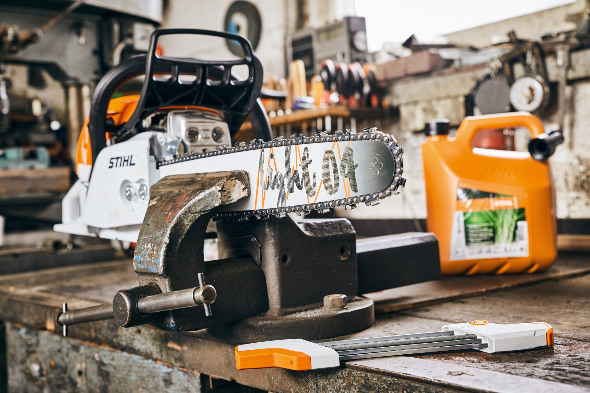 STIHL MS 261 C-M petrol chainsaw with Light 04 guide bar next to STIHL MotoMix fuel mixture before sharpening