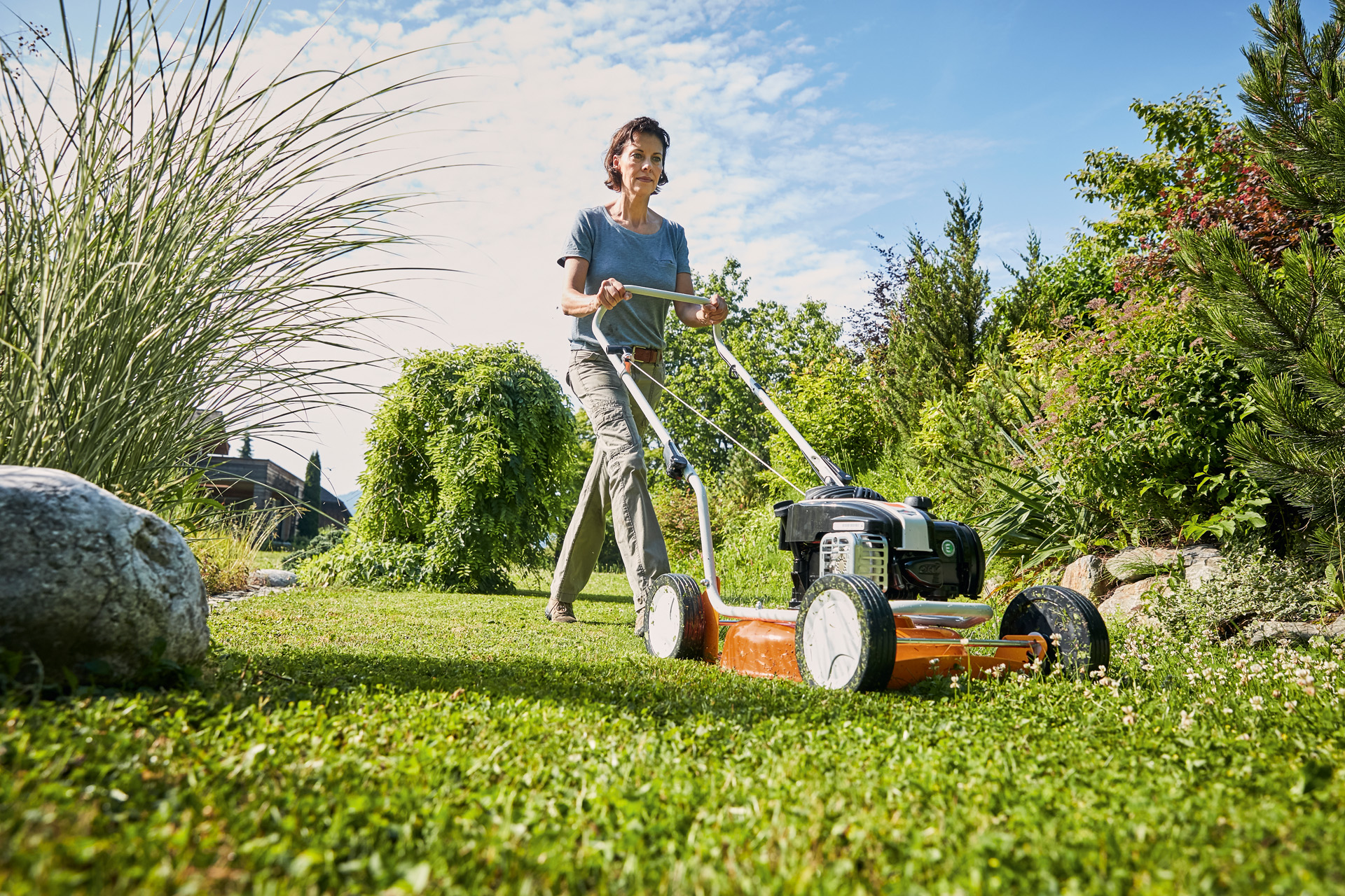 Femme en train de tondre avec une tondeuse mulching thermique STIHL&nbsp;RM&nbsp;2&nbsp;R sur un terrain gazonné