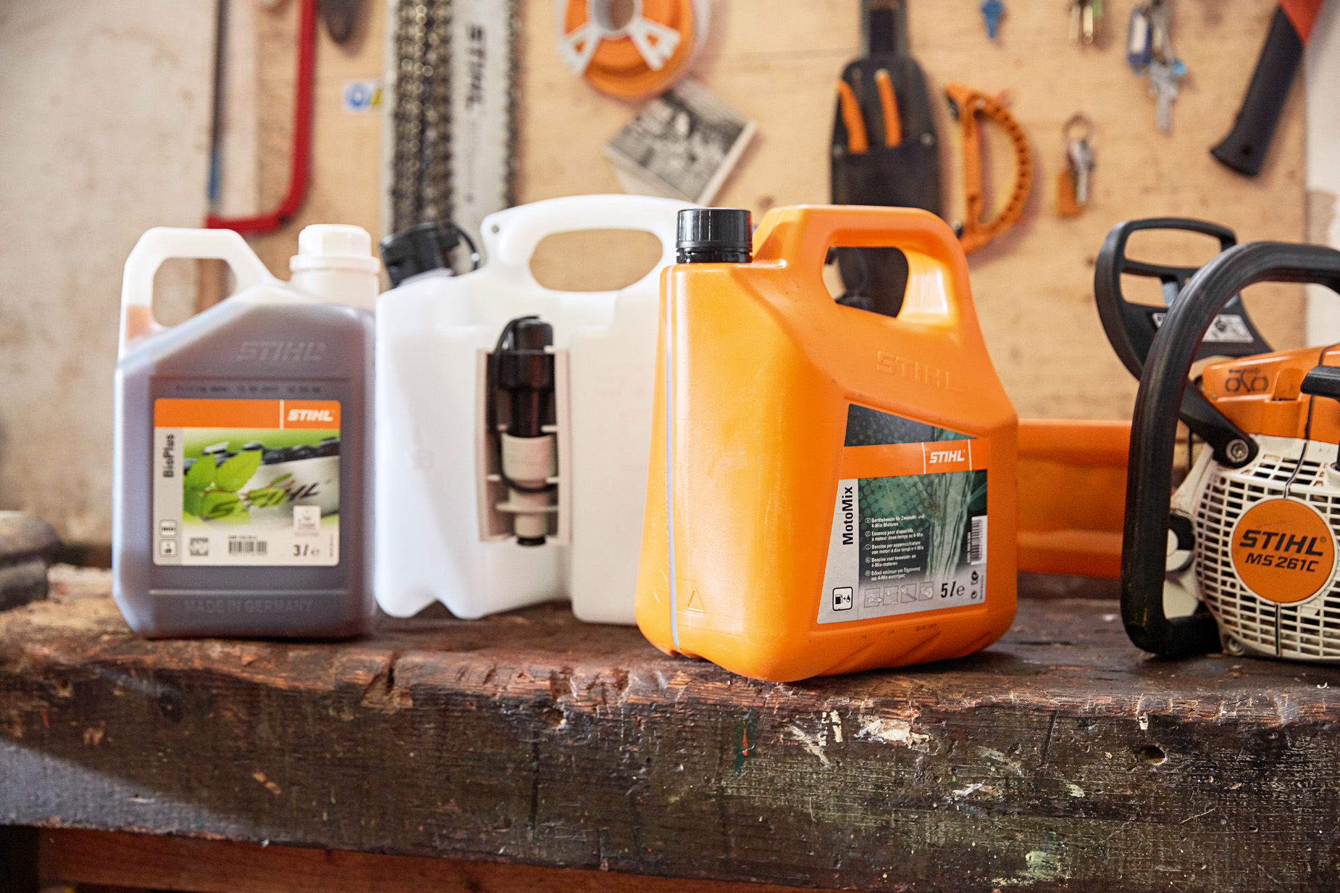 A combination canister on a tool bench in between canisters of STIHL MotoMix and BioPlus chain oil