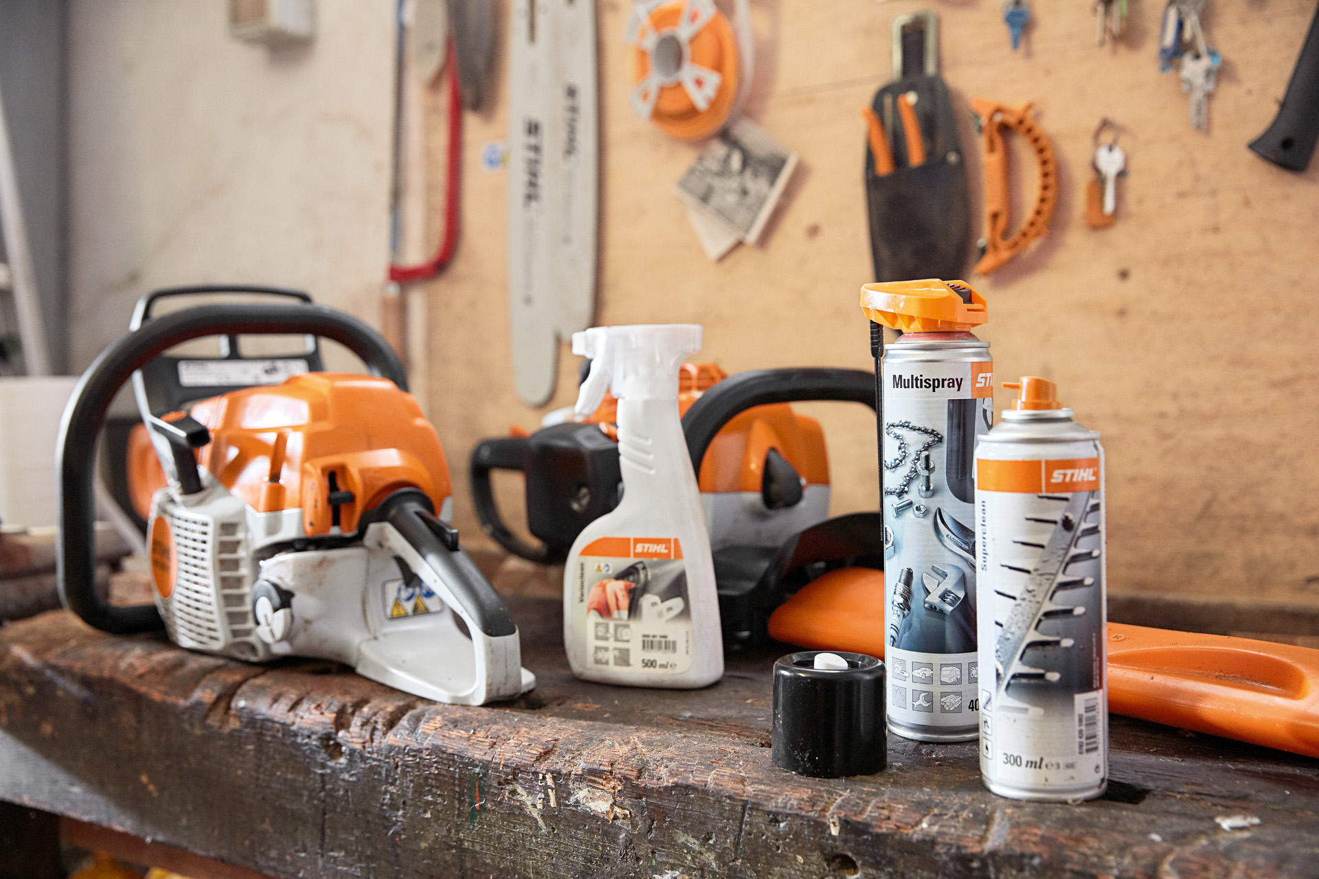 A workbench with several STIHL products on it: a chainsaw, Varioclean, Multispray and Superclean resin solvent