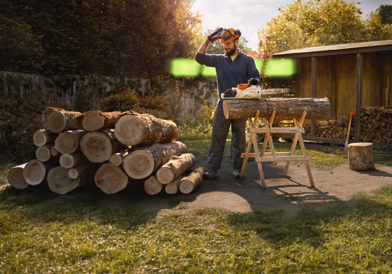 An individual using a STIHL battery chainsaw to cut wood.