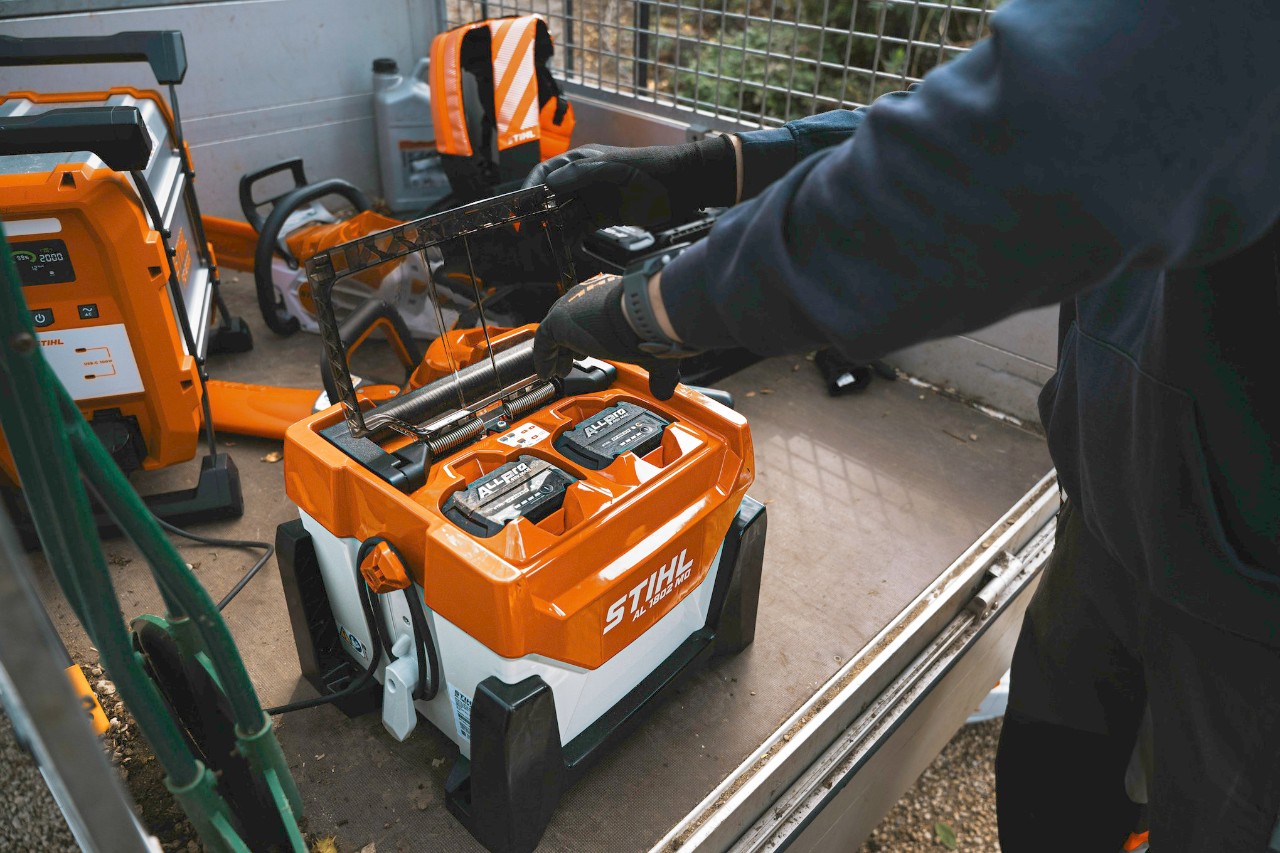A man inserts an ALLPRO battery into a fast charger