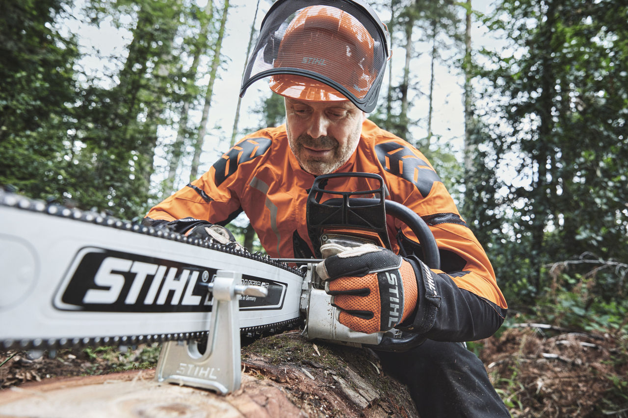 Un homme en équipement de protection travaille en forêt avec une tronçonneuse STIHL