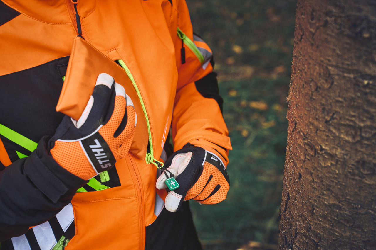 Gros plan d'une personne en STIHL ADVANCE FlexTEC avec pendentif à fermeture éclair de premiers secours ShellTEC dans la forêt