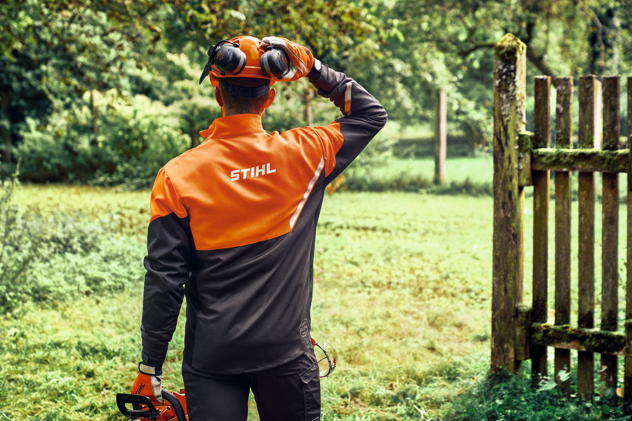 Dos d'un homme portant la veste STIHL Function Core avec protection de la tête et des oreilles